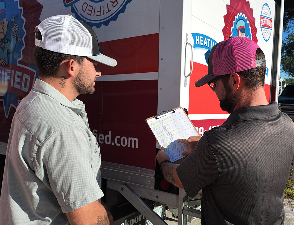 a Certified technician talks with a client in front of their hvac truck
