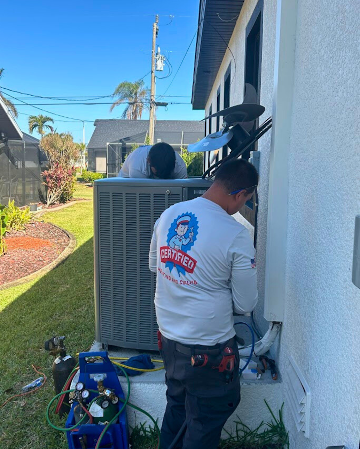 Two Certified technicians outside, working on an HVAC unit
