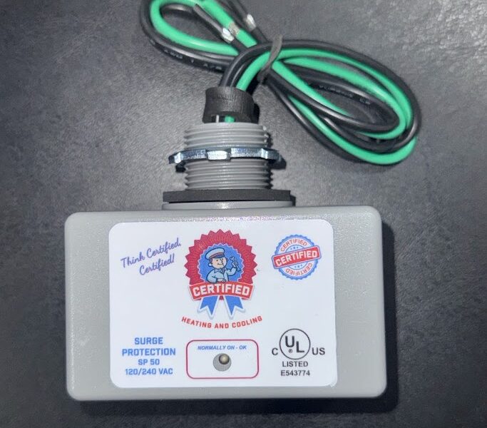 A gray surge protector for Southwest Florida homes sits on a dark surface, showing green, black, white wires, labels, and a UL mark.