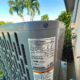 An outdoor AC unit sits by a house, with spec and warning labels; palm trees and bushes stress HVAC maintenance in SW Florida.